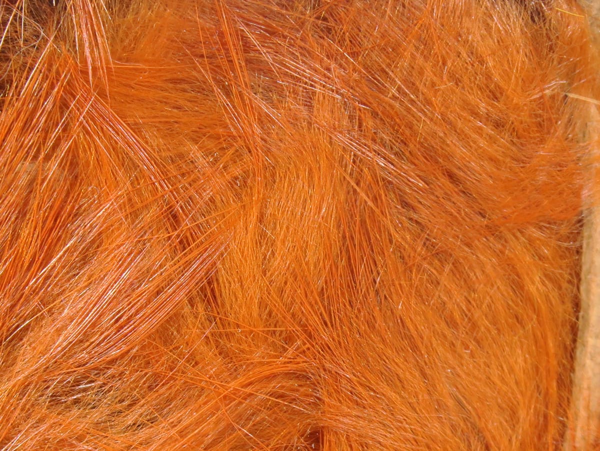 Bright orange Hareline Magnum rabbit fur strips, close-up of soft glossy long fur strands for fly tying
