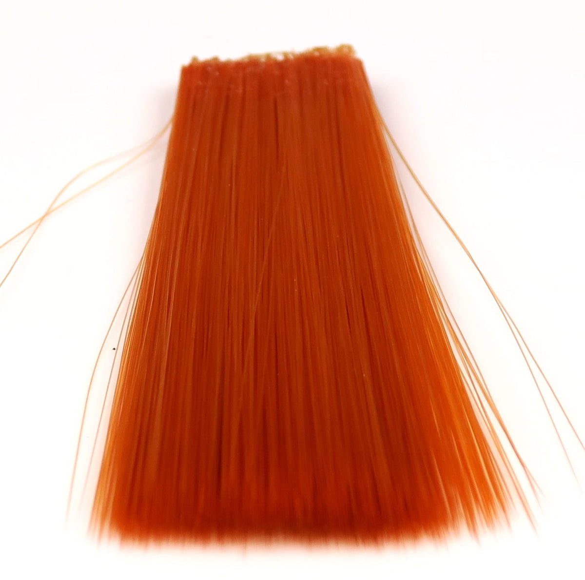 Rust-orange synthetic mayfly tails bundle with long straight fibers glued at top for fly tying