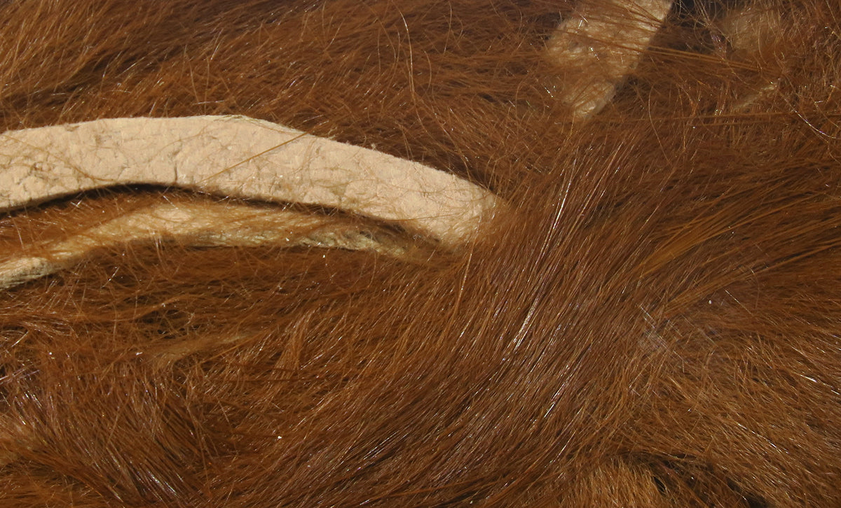 Hareline micro rabbit fur strips in chestnut brown showing fine soft hairs and beige leather backing for fly tying