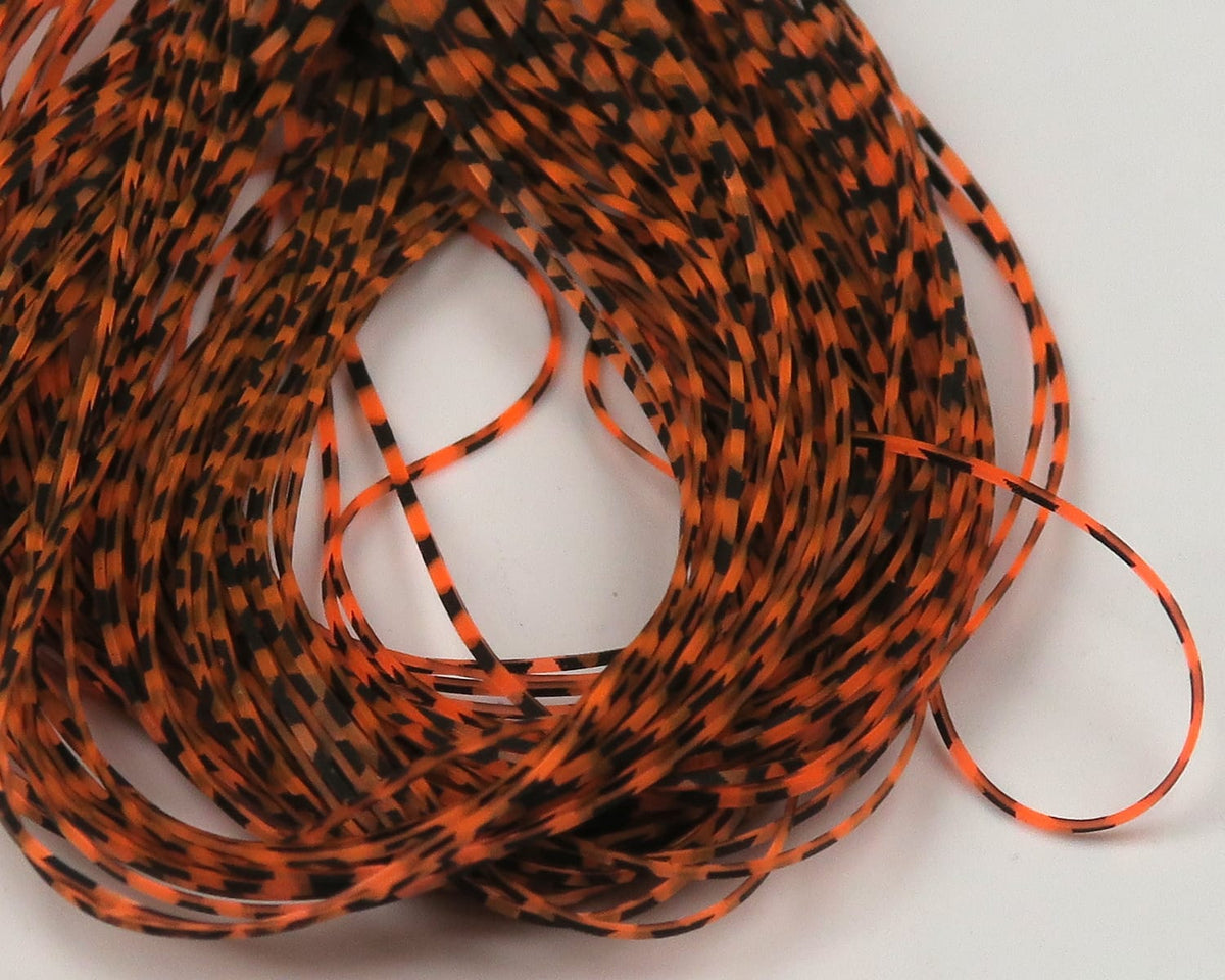Coiled orange and black micro silicone legs, thin striped and speckled fly tying material on white background