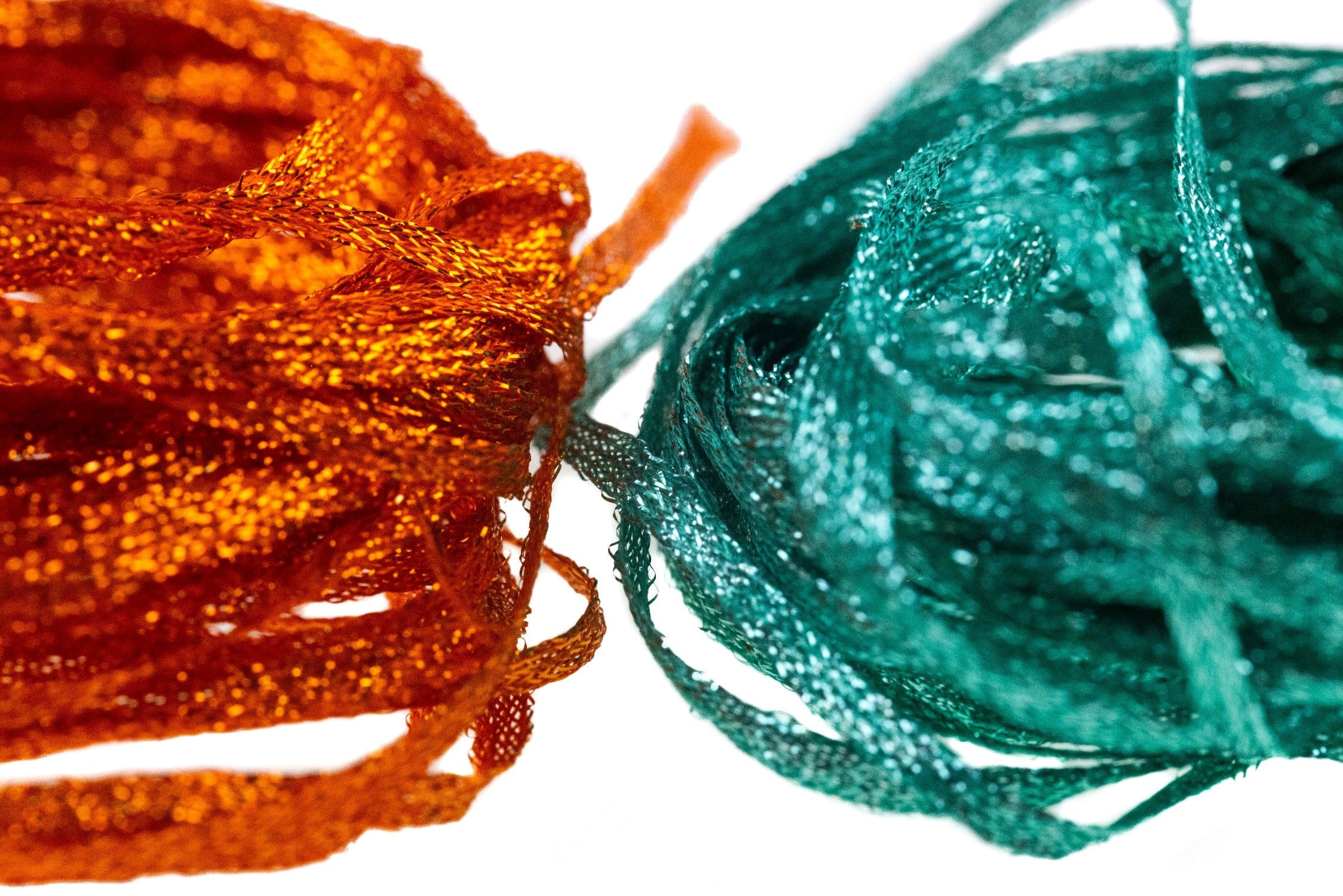 Hareline flat fly braid bundles in metallic orange and teal, braided synthetic strands with glittery shimmer