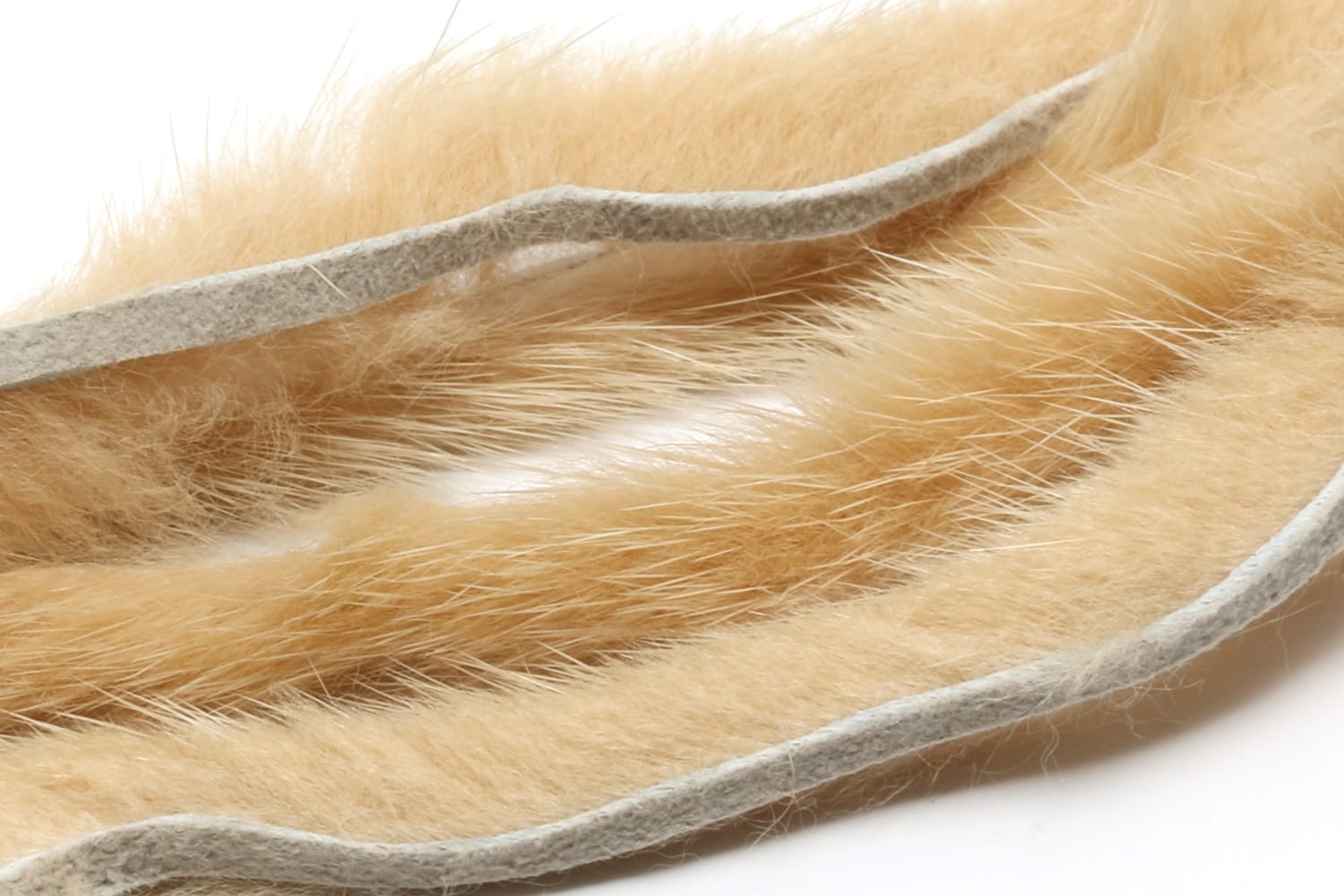 Hareline mink strips in warm tan mink fur with pale gray felt backing, fluffy fur and guard hairs for fly tying