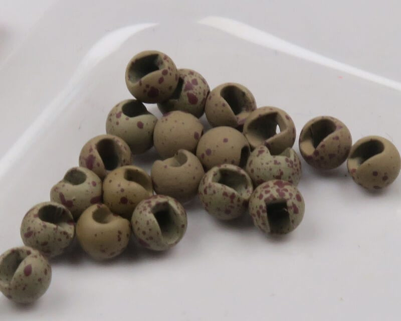 Mottled tan-olive slotted tungsten beads with maroon speckles, round matte fly tying beads on white background