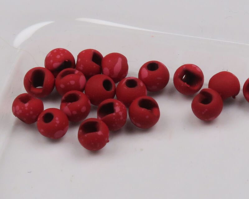 Mottled matte red slotted tungsten beads with pale speckles, round fly tying beads arranged on white background