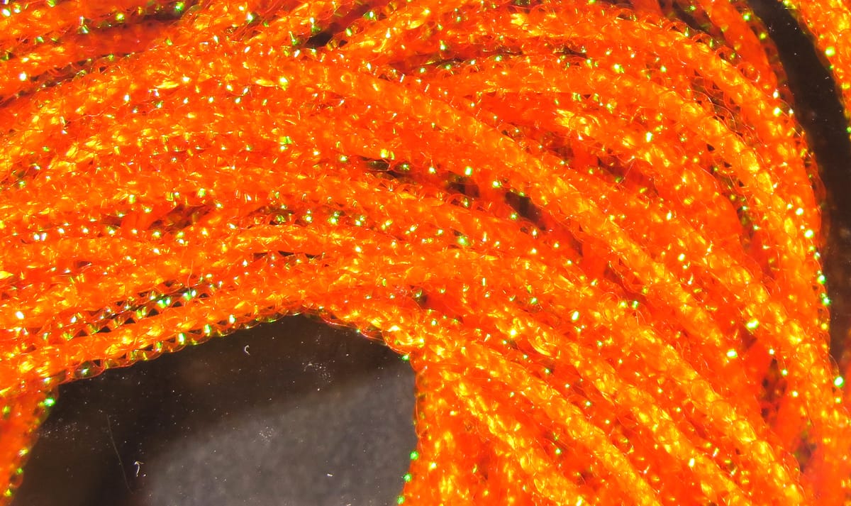 Bright orange Hareline Pearl Core Braid, closeup pearlescent braided fly-tying material with green iridescent flash