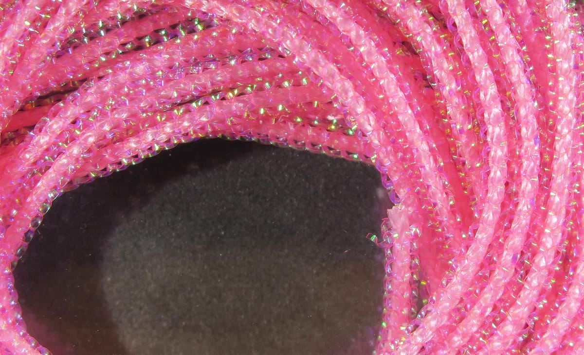 Bright pink Hareline pearl core braid with iridescent green flashes, translucent braided tubing for fly tying