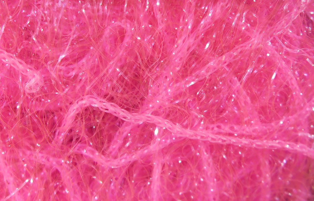 Hot pink polar chenille close-up showing fluffy synthetic fibers with iridescent tinsel strands for fly tying