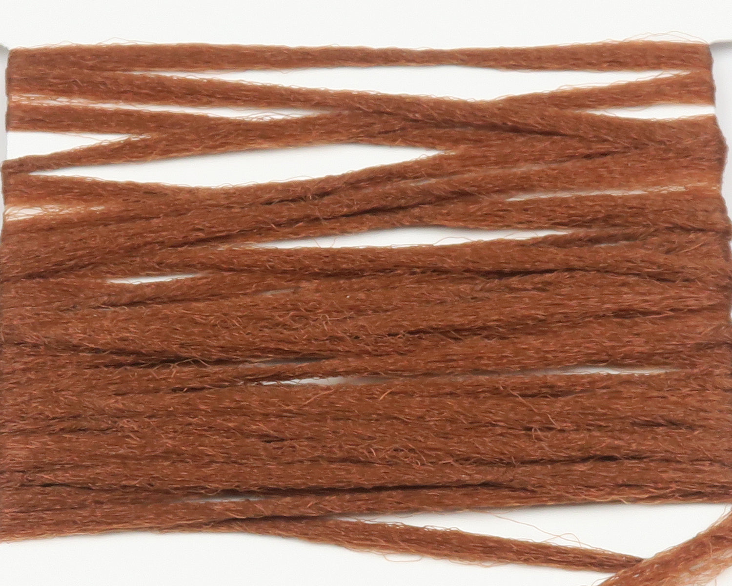 Hareline rust brown polypropylene floating yarn, fuzzy flat strands arranged on white backing