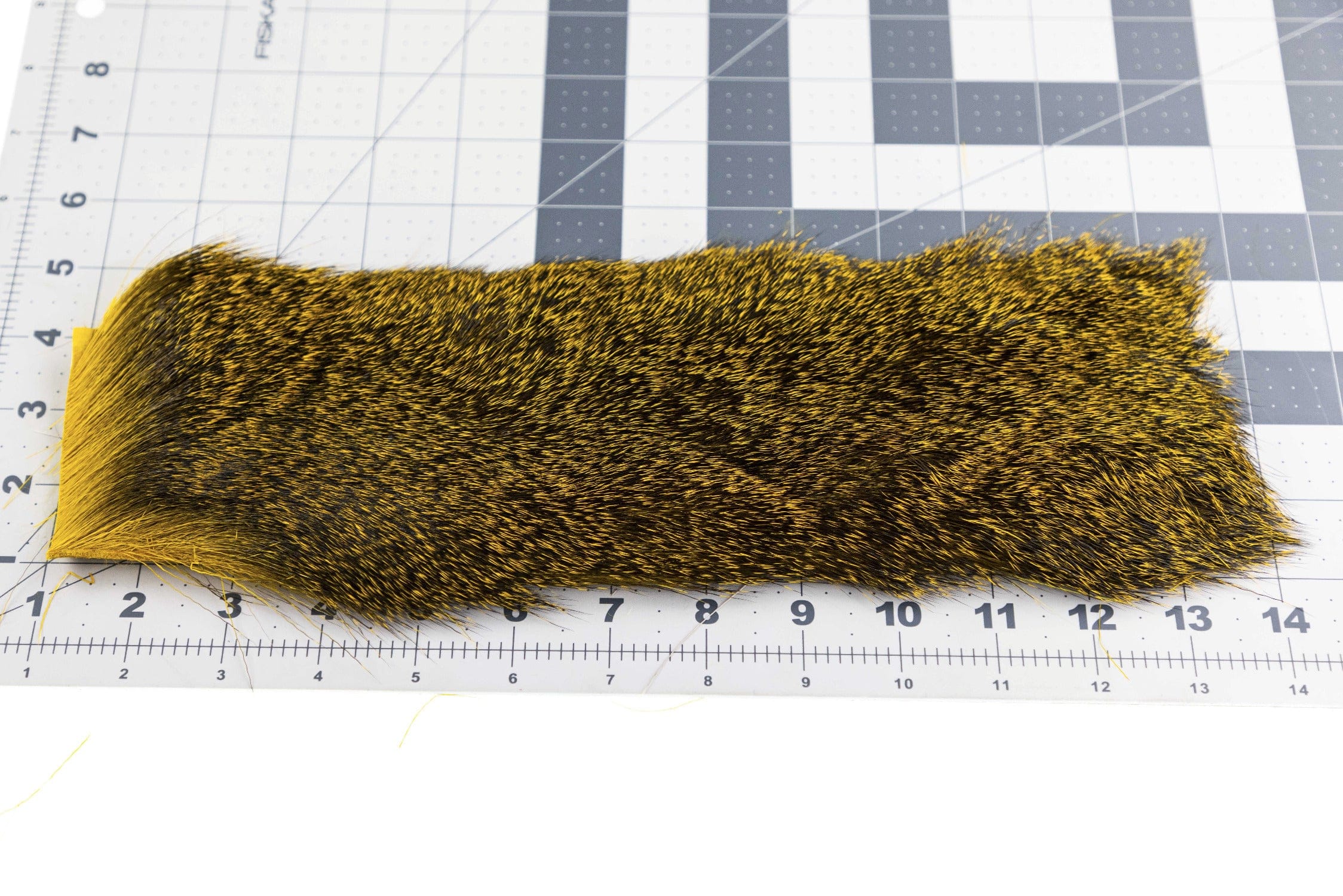 Black and golden-yellow deer hair strip with dense speckled texture, long fur strip for fly tying displayed on measuring mat