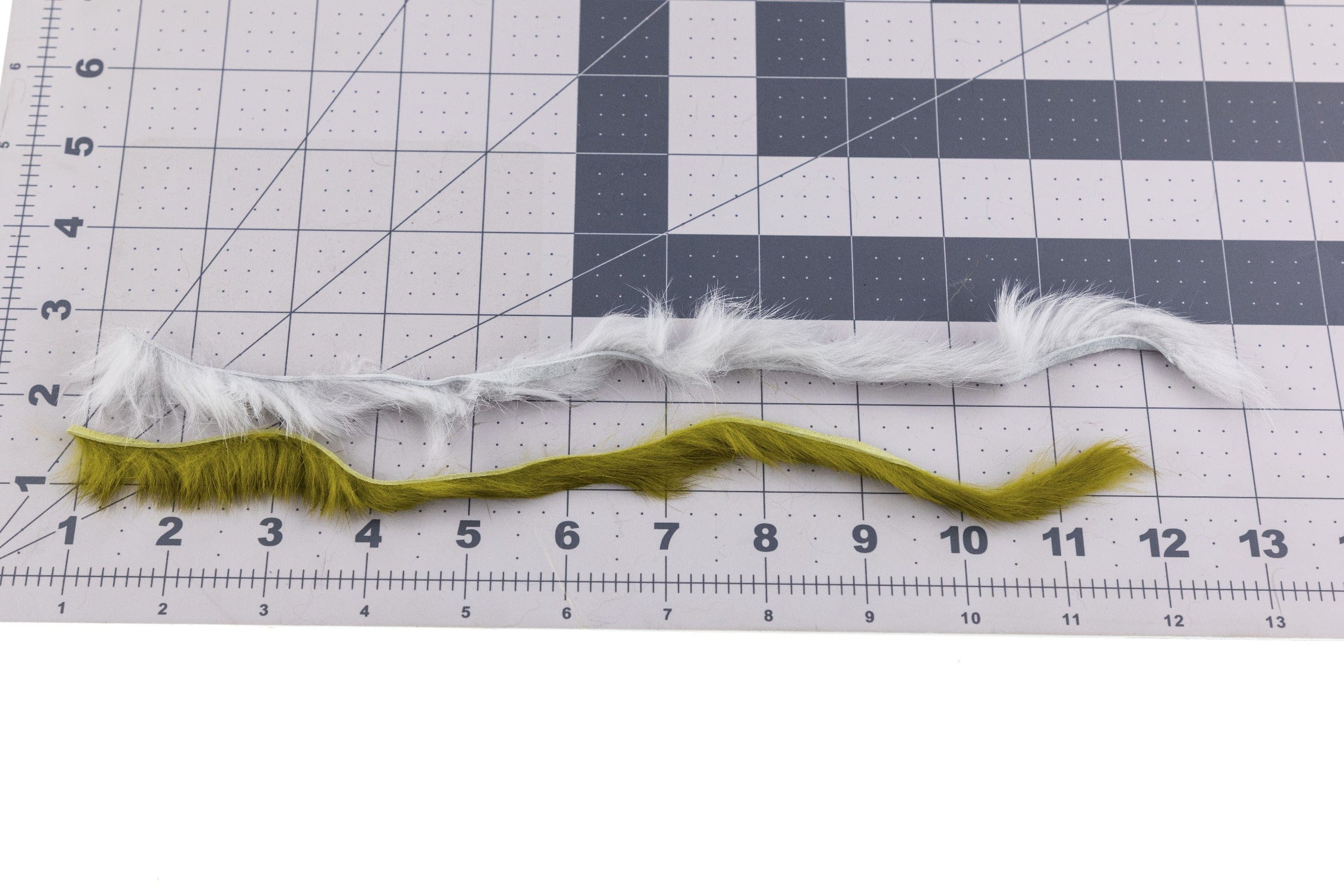 Hareline rabbit fur strip combo: long fuzzy strips in light gray and olive with backing laid on measuring grid for fly tying
