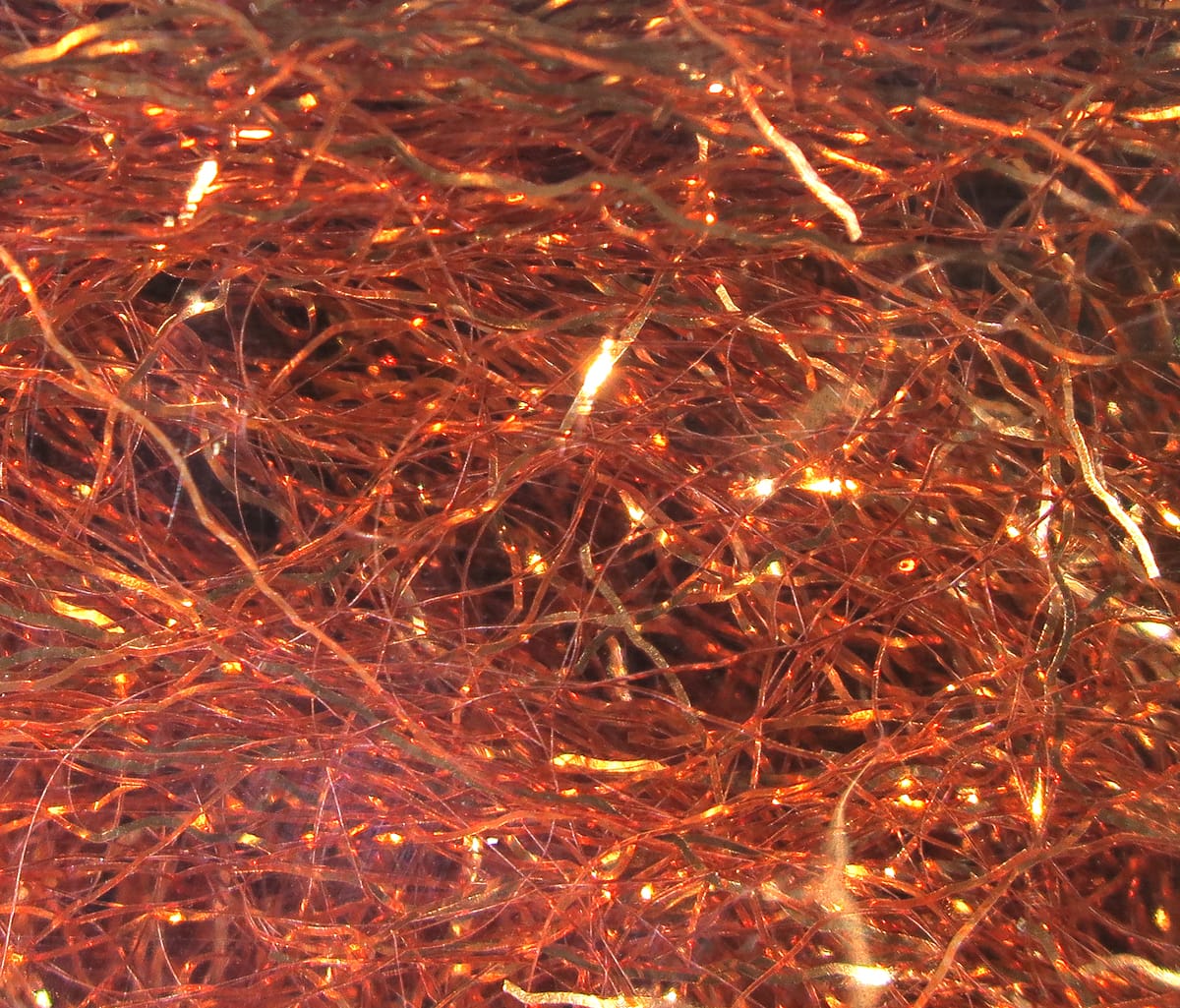 Copper-orange iridescent synthetic ripple fibers for fly tying, tangled shimmering strands with metallic highlights