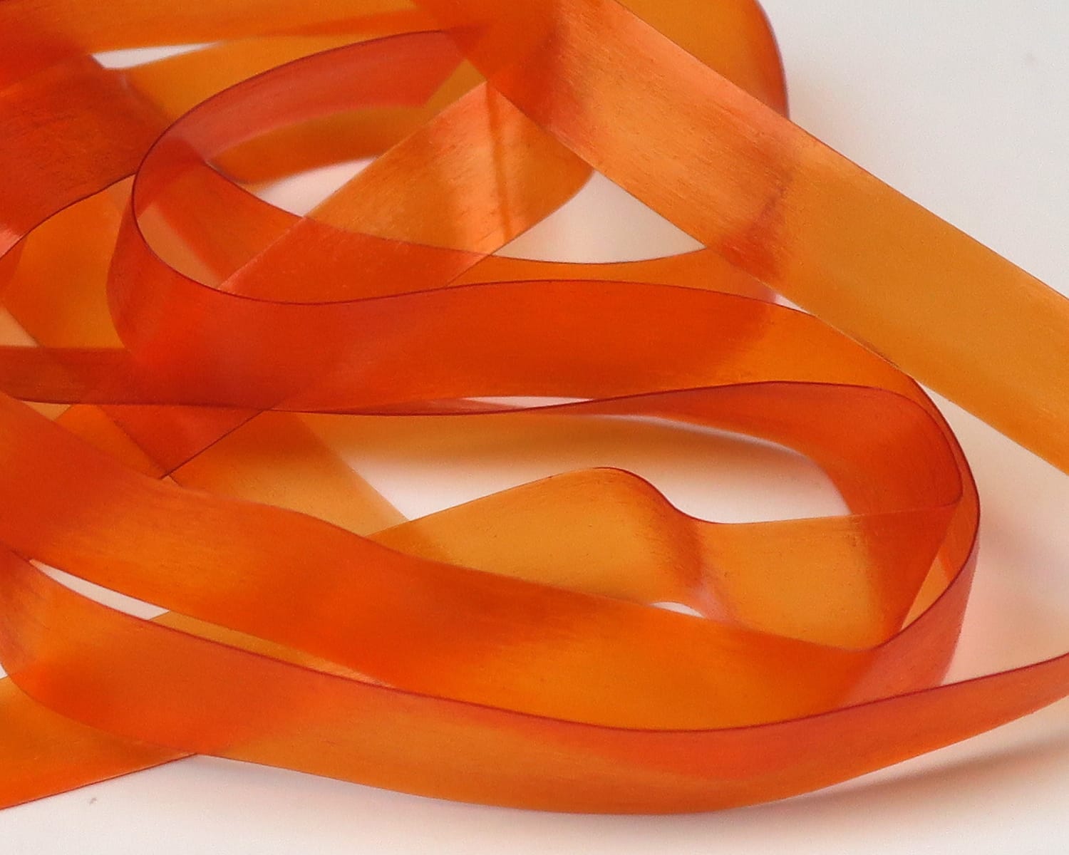 Translucent orange Hareline Scud Back ribbon, flexible shiny rubbery strip used as scud back material for fly tying.