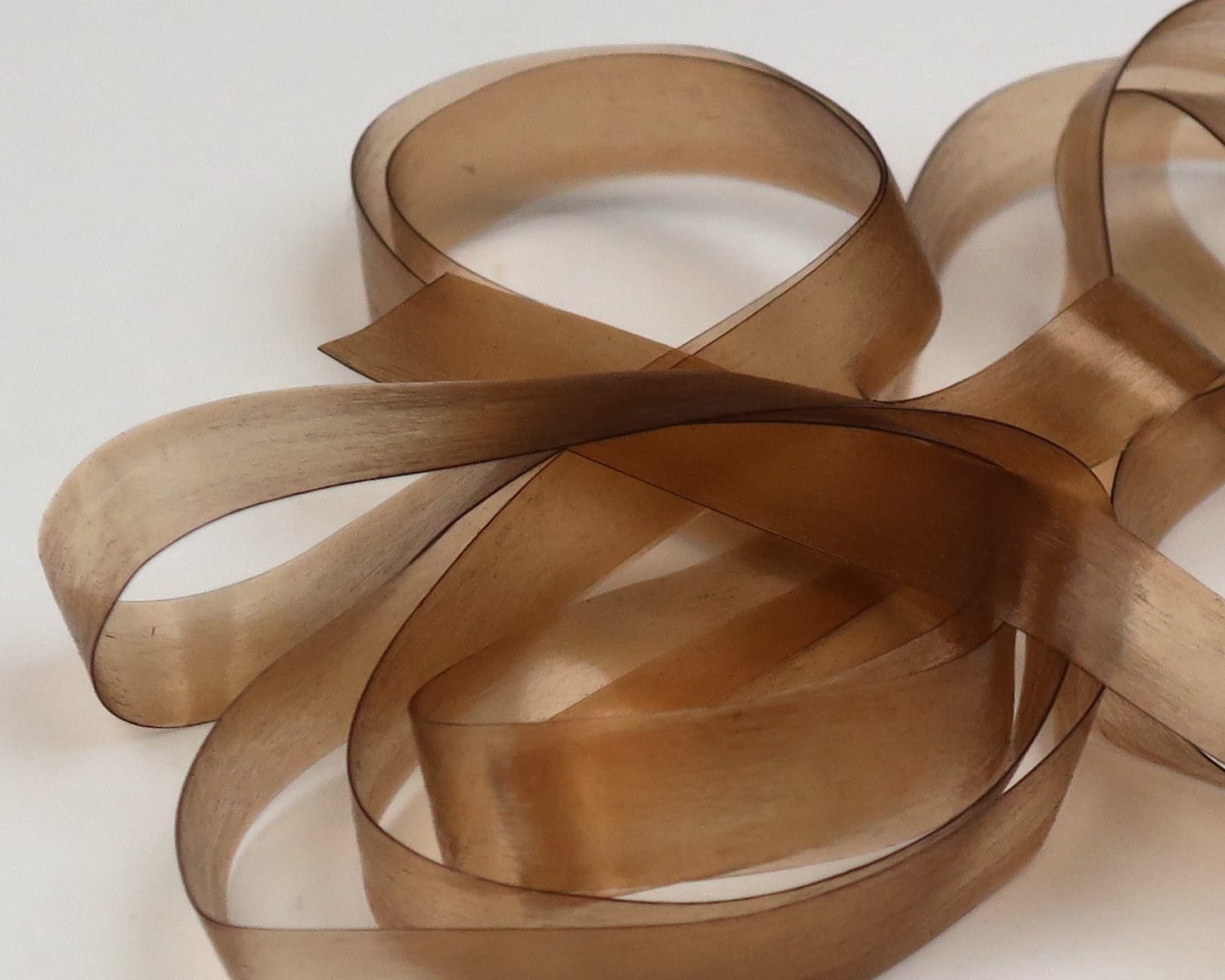 Hareline Scud Back translucent tan synthetic ribbon strips for fly tying, smooth glossy scud-style material looped