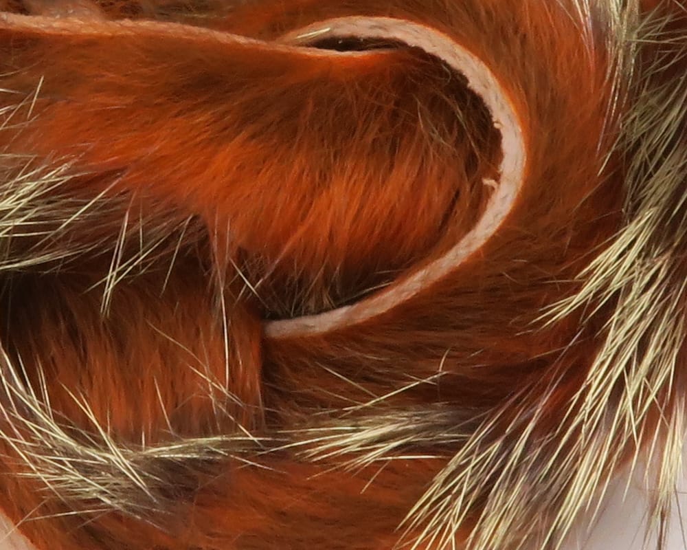 Shimmer rabbit fur strips in copper orange with glossy guard hairs and pale strip backing for fly tying