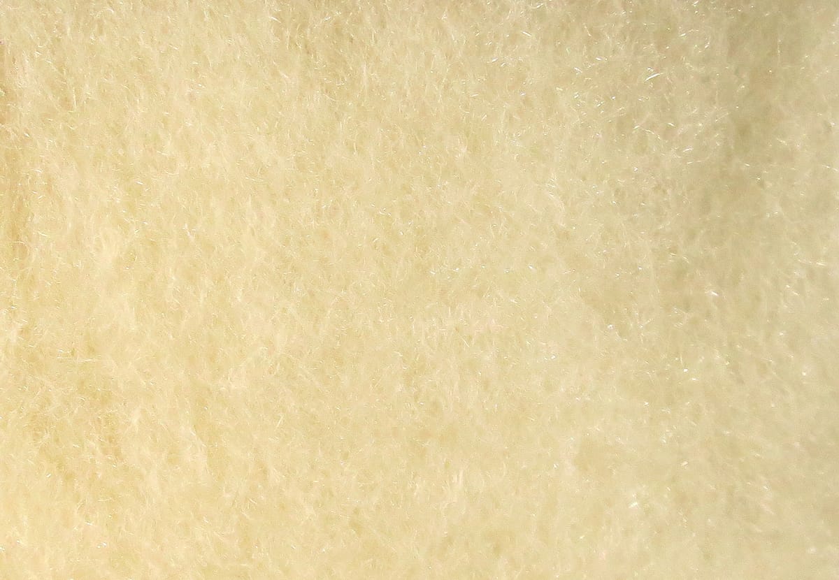 Cream Hareline super fine dry fly dubbing close-up showing soft fibrous texture with subtle iridescent sparkle for fly tying