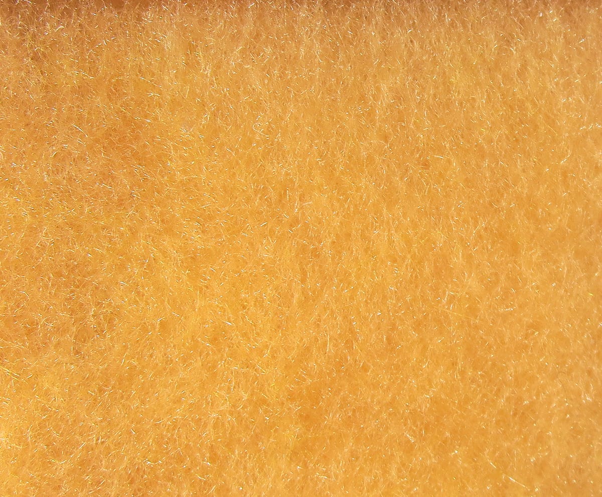 Golden-orange fine synthetic dry fly dubbing with short fibrous texture and subtle iridescent sparkle for fly tying