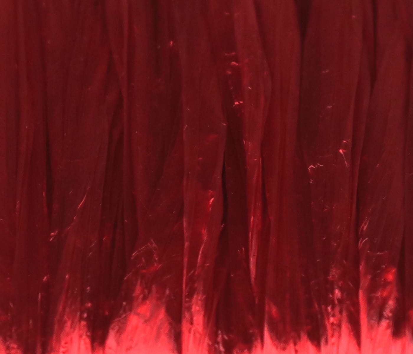 Deep red Hareline Swiss Straw sheets with glossy translucent crinkled plastic strips for fly tying material