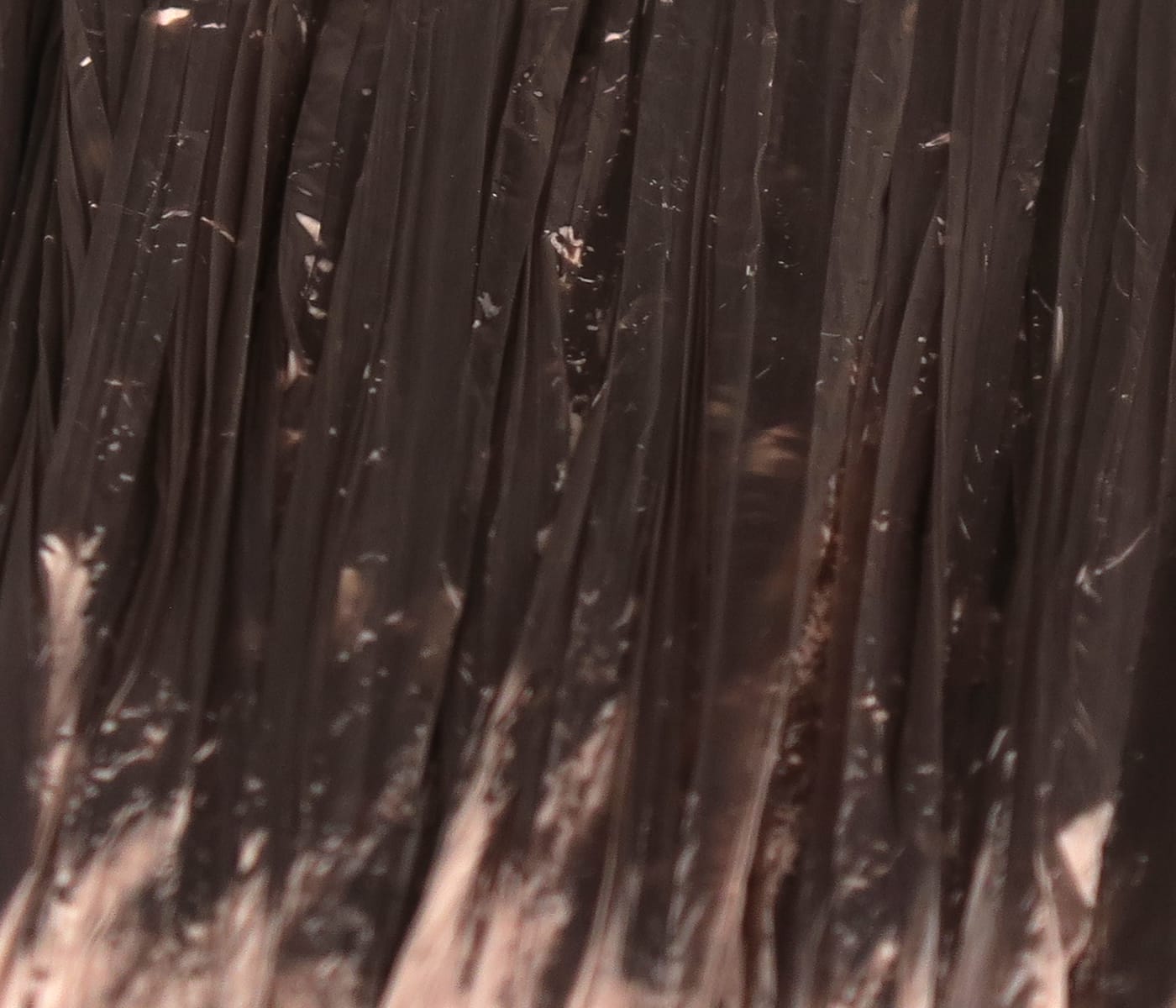 Close-up dark brown Swiss Straw fly tying material, glossy thin translucent plastic straw fibers bundled