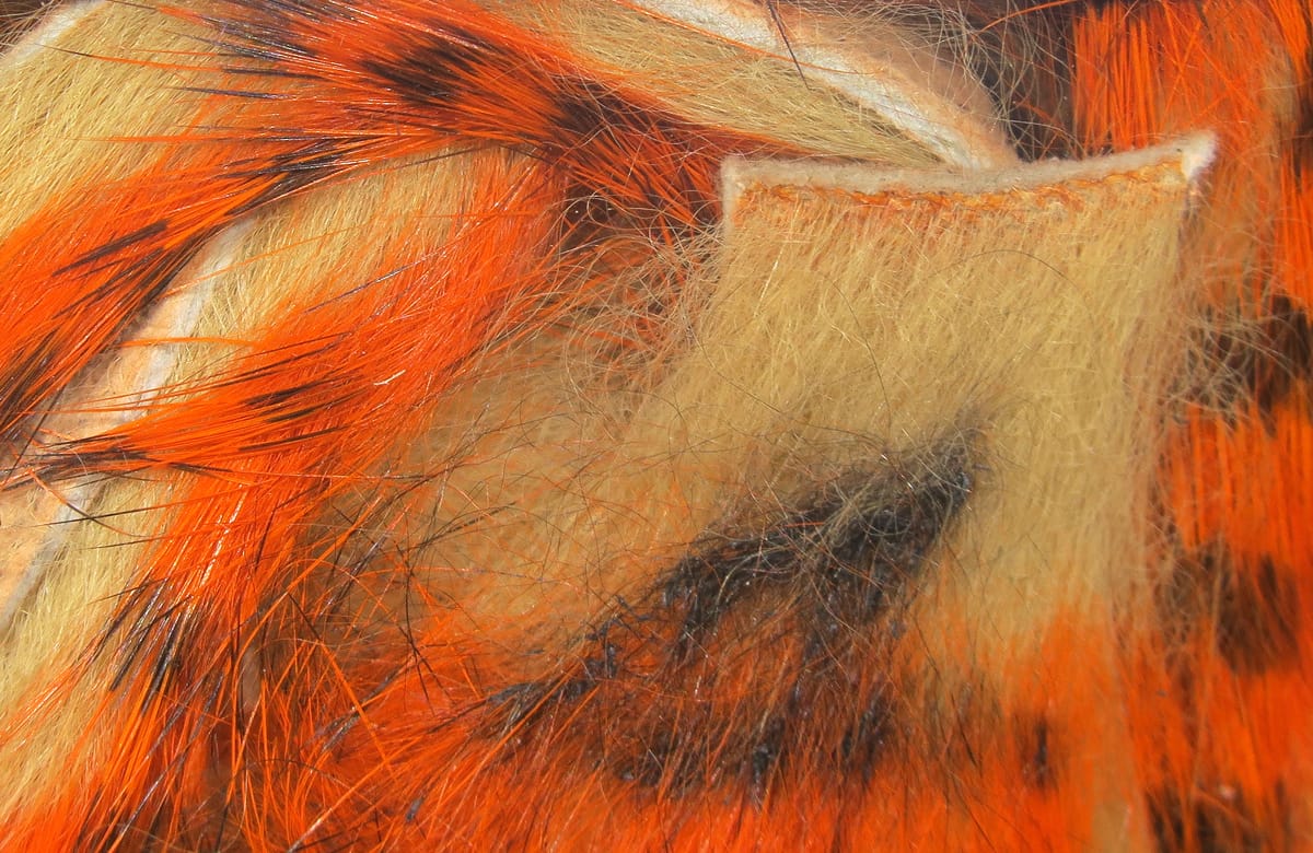 Orange and tan tiger-barred rabbit fur strips with black barring and long guard hairs, soft fur ideal for fly tying