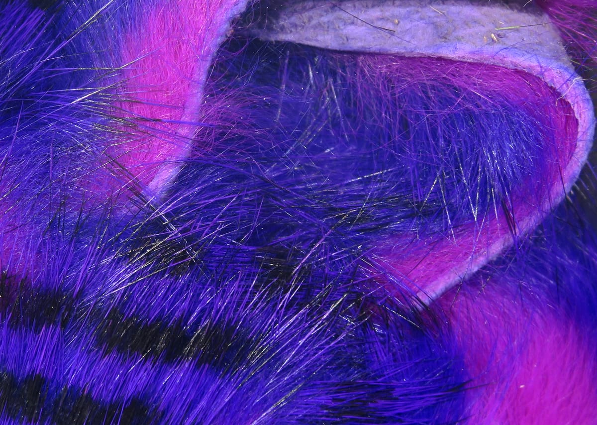 Purple and magenta tiger-barred rabbit fur strips with black bars and glossy guard hairs on leather backing, for fly tying