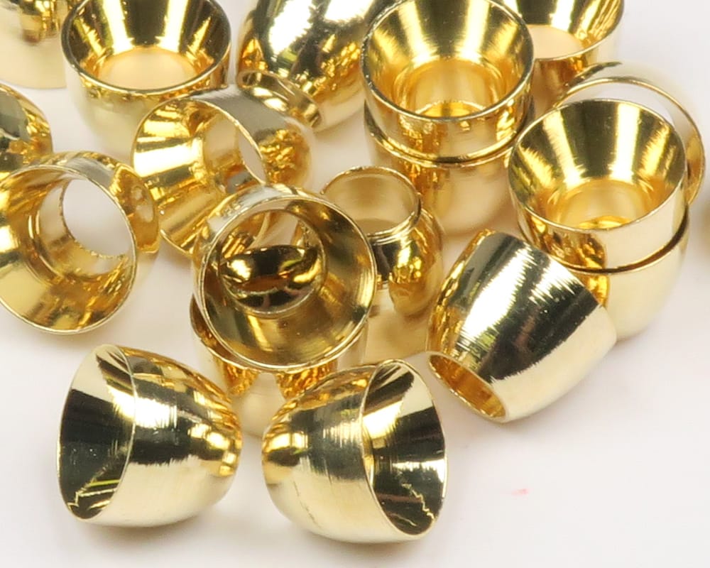 Shiny gold tube cone heads with polished brass finish, cone-shaped fly tying beads scattered on white background