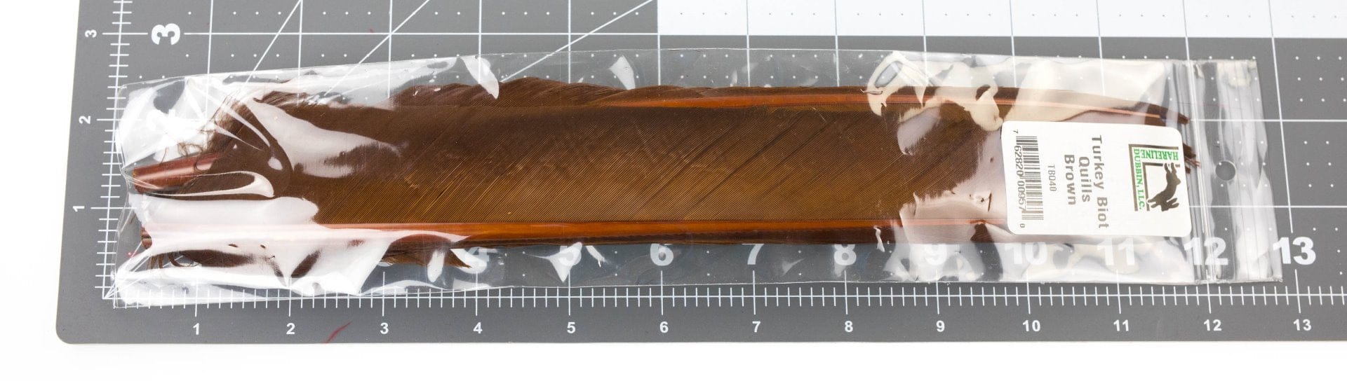 Brown glossy turkey biot quills in clear plastic pack, long narrow feather strips with orange edges for fly tying