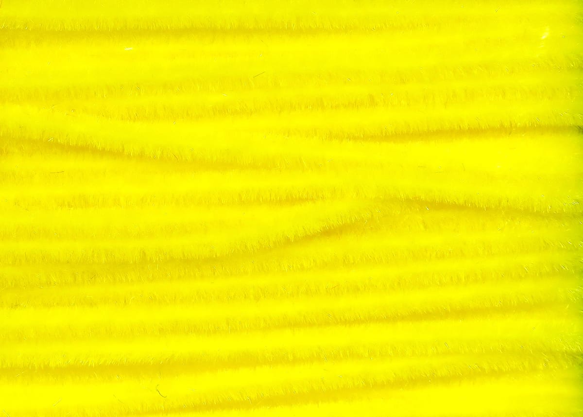Bright fluorescent yellow Hareline Ultra Chenille, fuzzy synthetic fibers in parallel ribbed rows for fly tying.