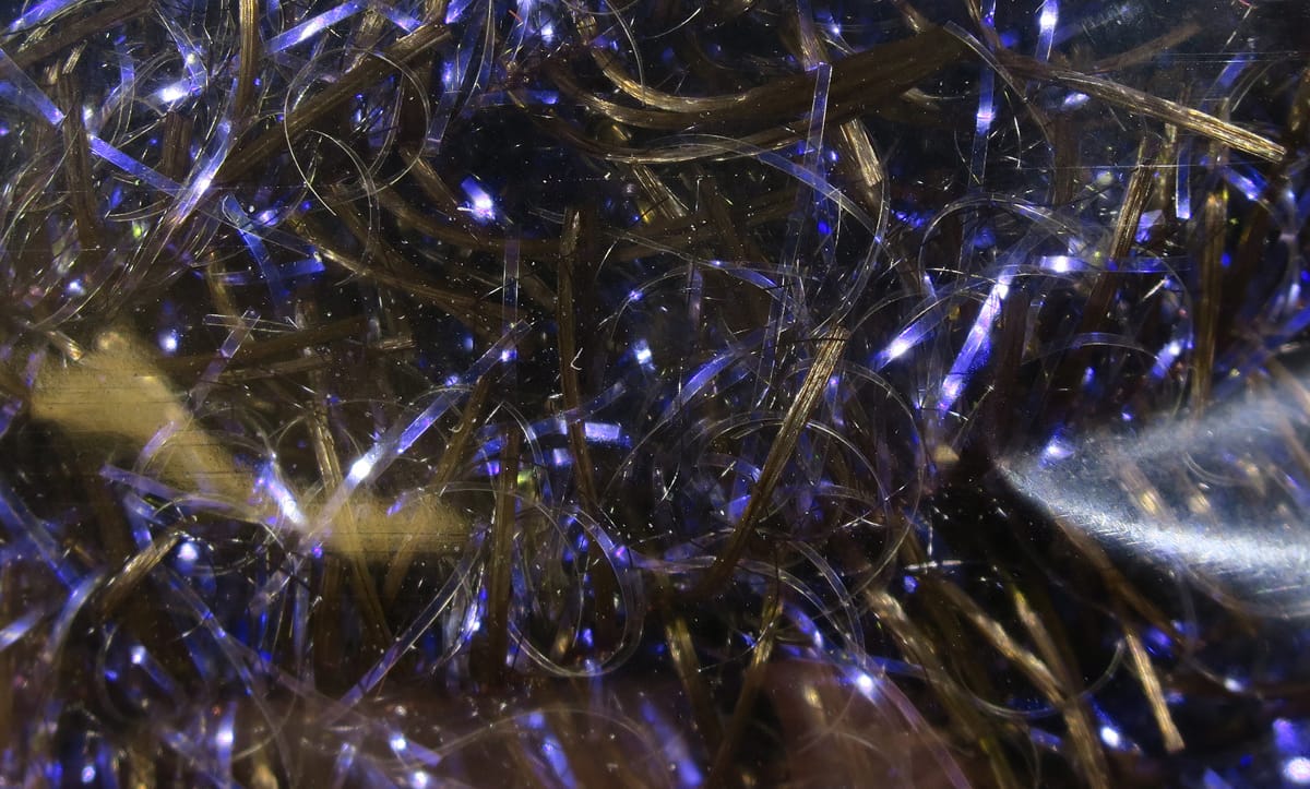 Hareline UV Life Flex Wrap: olive-brown synthetic fibers with purple-blue iridescent flash, thin fly-tying strands