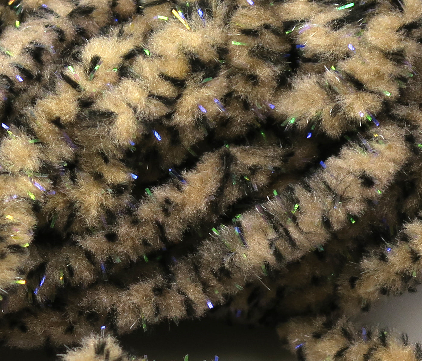 Beige and black mottled mop chenille with iridescent green-blue UV flash fibers for fly tying