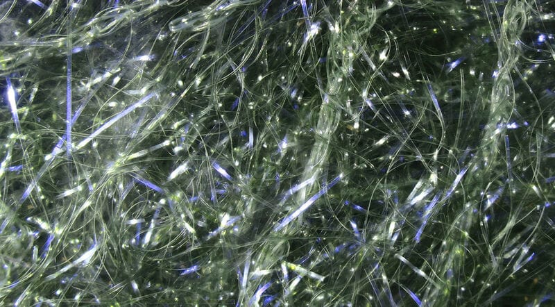 Tangled translucent green-gray synthetic fibers with iridescent blue flashes, UV polar chenille for fly tying