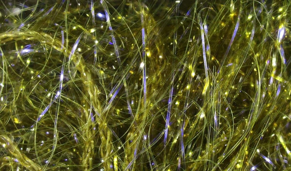 Olive-yellow Hareline UV polar chenille closeup showing fine translucent fibers and iridescent blue-green flash for fly tying