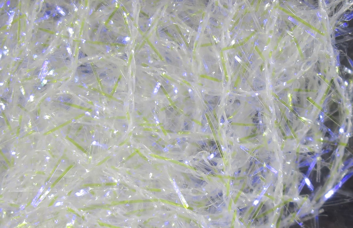Translucent white iridescent UV polar chenille with thin lime-green strands and sparkling tinsel fibers for fly tying