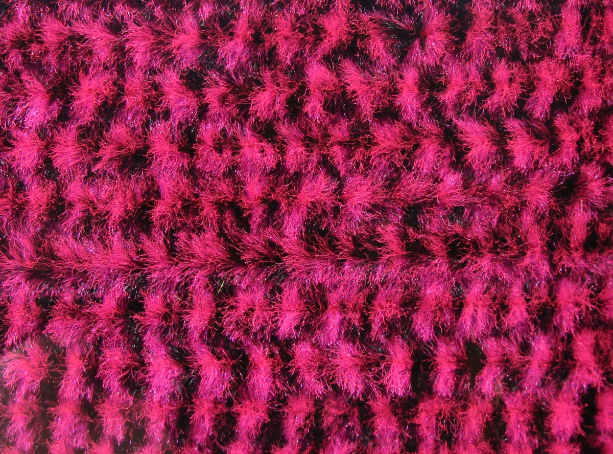 Variegated Hareline chenille in bright magenta and black, fuzzy iridescent fibers for fly tying lures