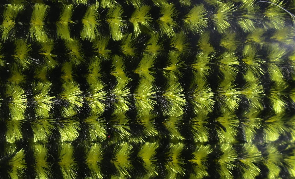 Variegated chenille in chartreuse and black, fuzzy striped fibers with glossy sheen for fly tying