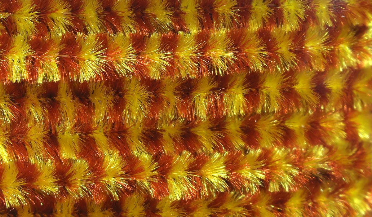 Variegated chenille strands in bright yellow and copper-orange, fuzzy metallic fly tying material