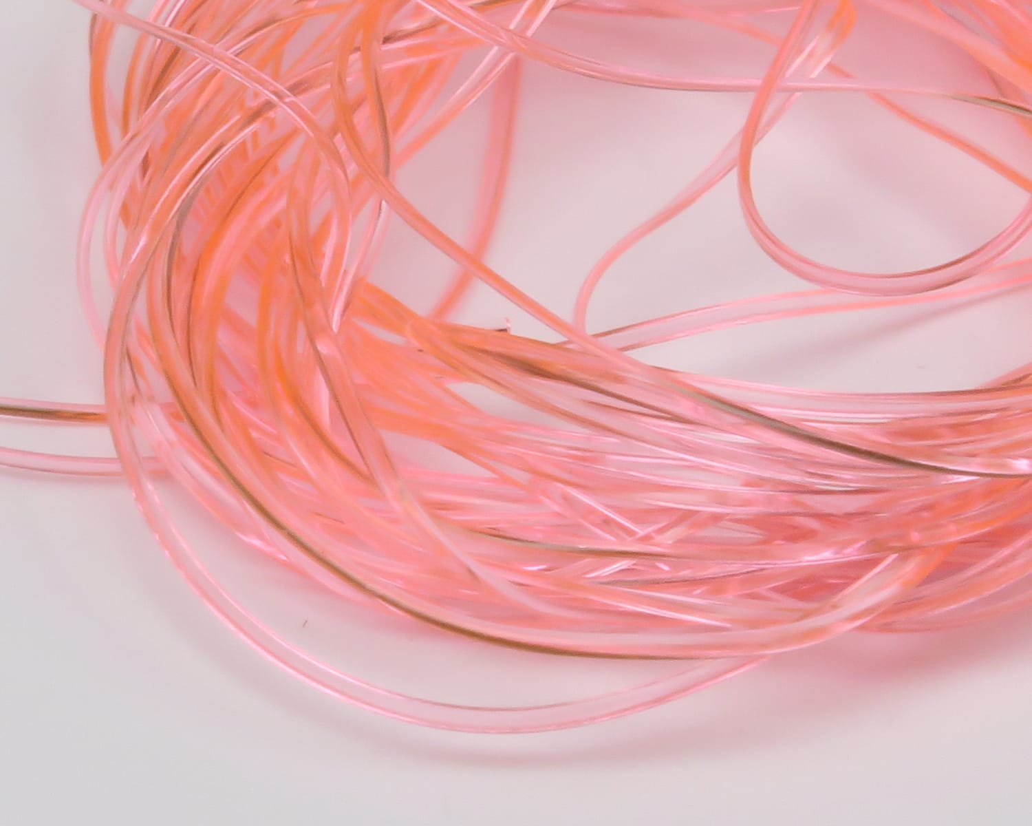 Pearl pink translucent coiled vinyl rib strands with subtle copper sheen, thin flexible fly tying material