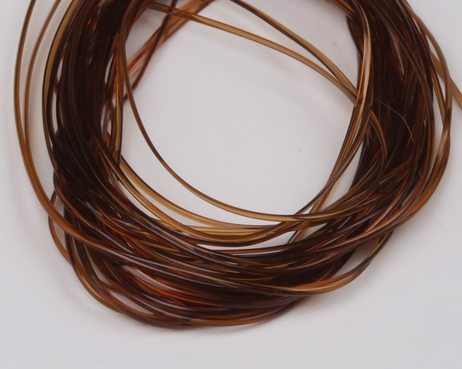 Hareline vinyl rib coil in translucent amber and brown, thin glossy plastic rib for fly tying