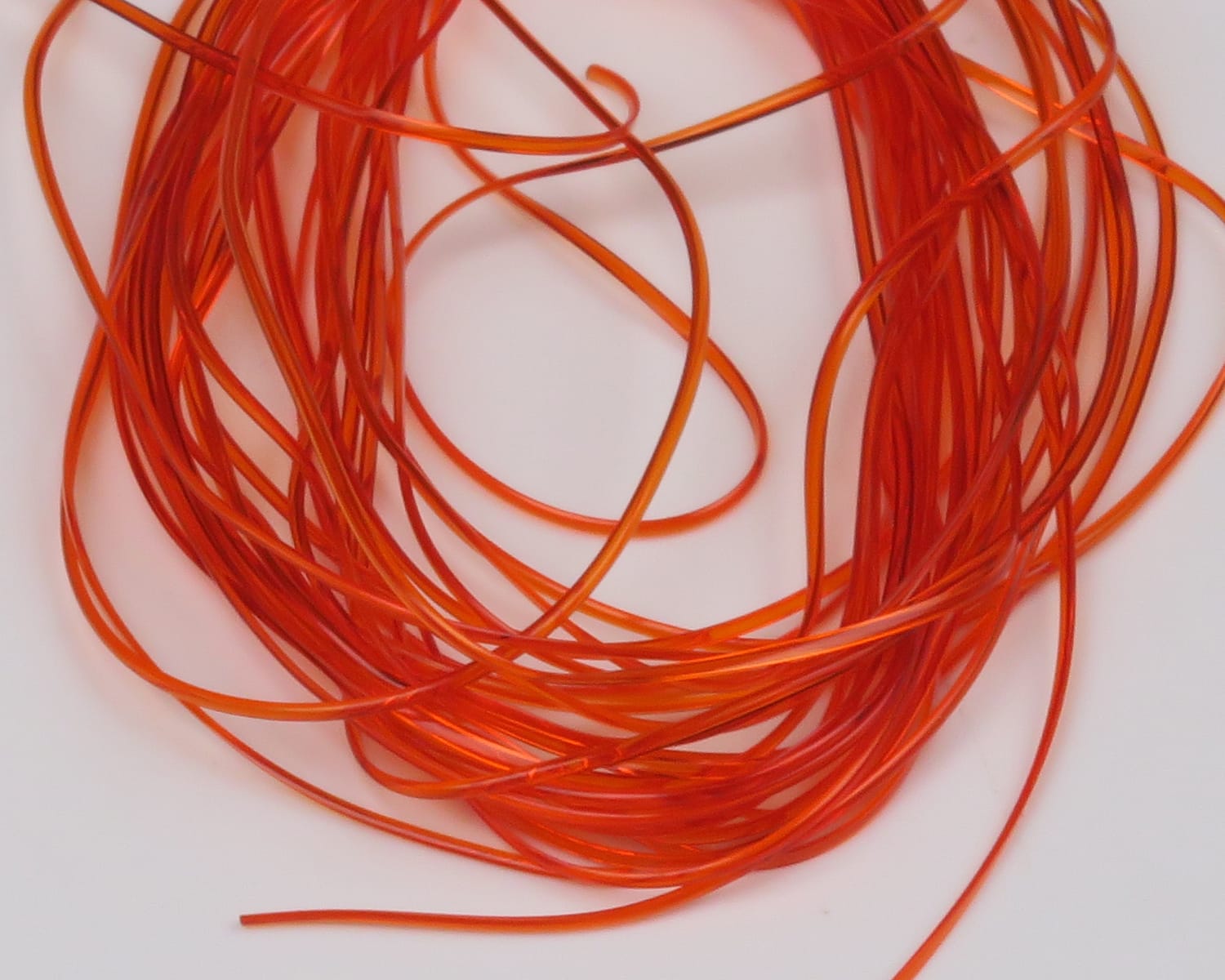 Hareline vinyl rib in bright orange, translucent flexible tubing strands coiled for fly tying