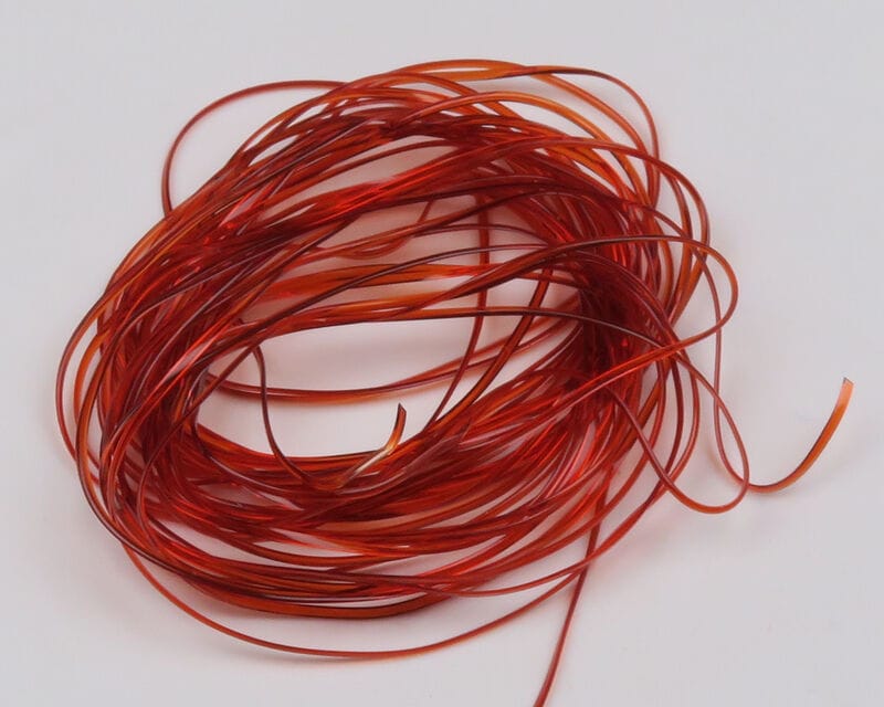 Coiled red-orange translucent vinyl rib for fly tying, thin flexible glossy strips