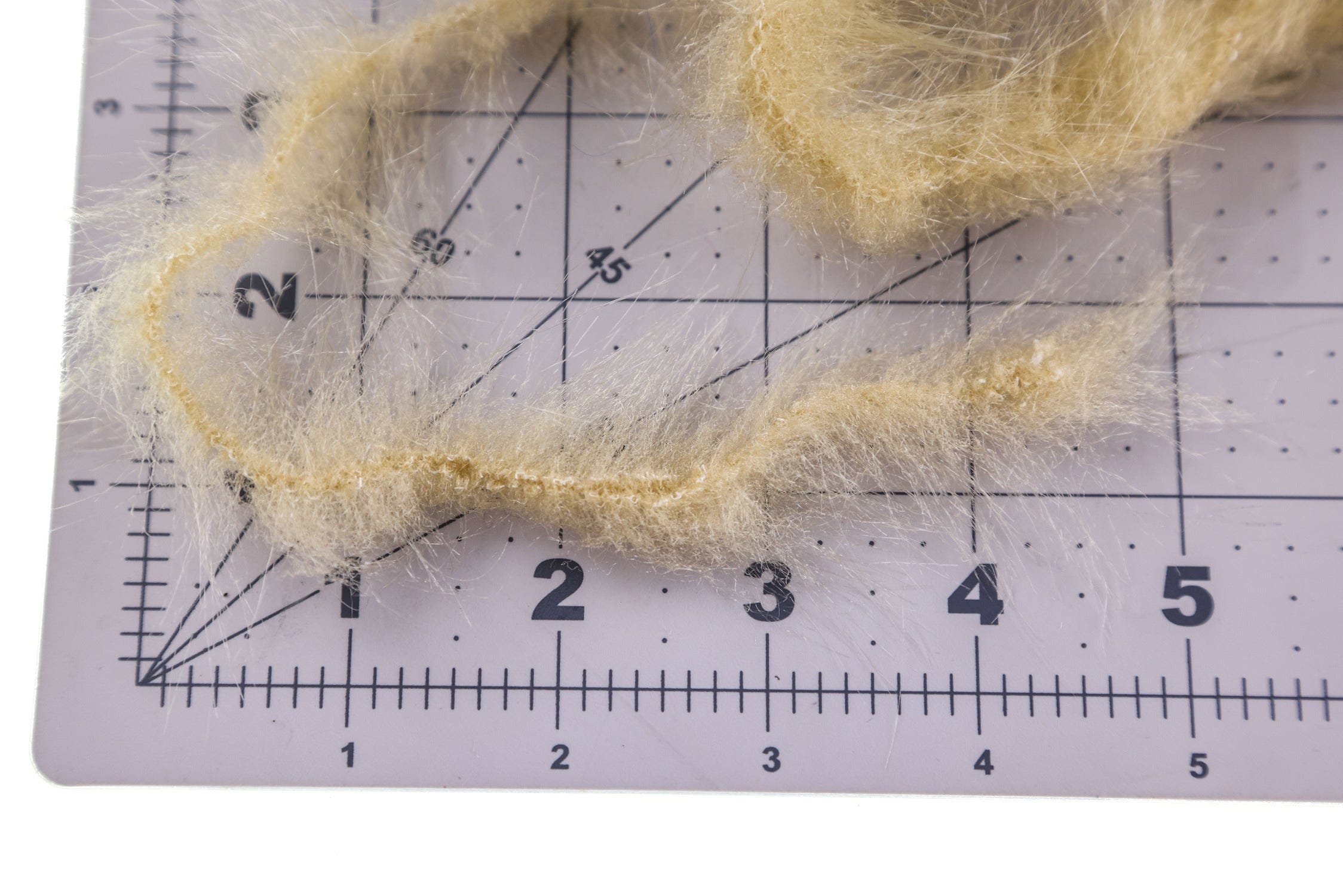 Pale tan Hareline wire-free synthetic fox brush with wispy synthetic fur fibers on gridded mat, fly tying material