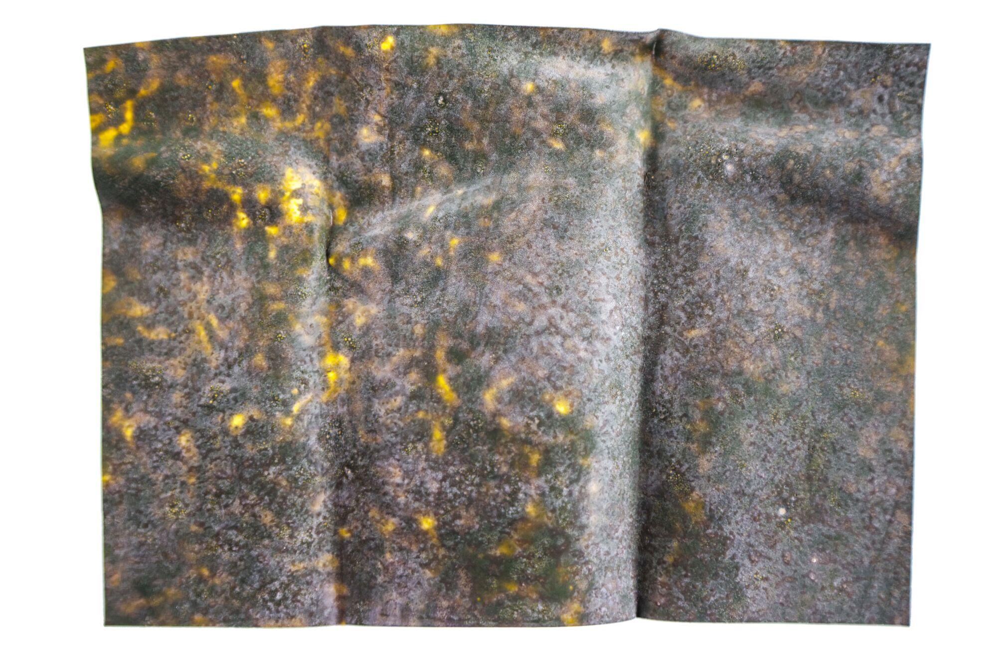 Wrinkled Kiley's Exo Skin sheet in mottled dark green and brown with bright yellow flecks, glossy textured fly tying material