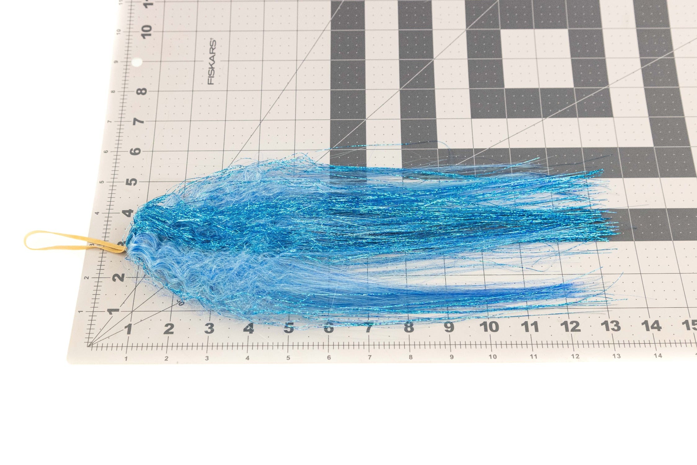 Bright blue Hedron fly tying fiber with curled synthetic strands and sparkling tinsel, long bundled taper with yellow loop