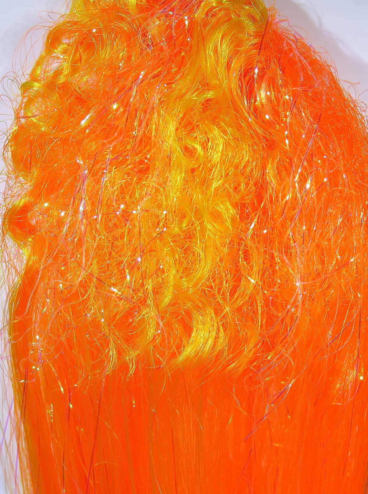 Bright orange and yellow Hedron Big Fly fiber with curly and long strands and iridescent tinsel for fly tying