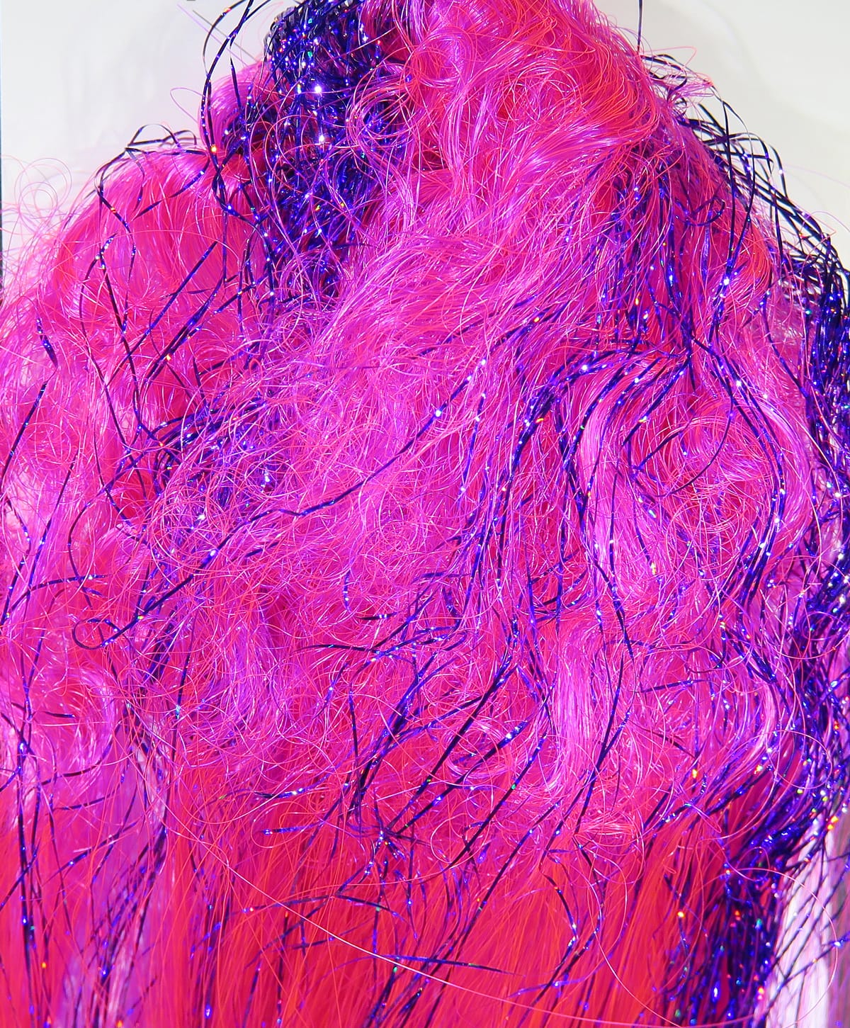 Bright hot pink synthetic fly tying fiber with curled iridescent purple flash strands, long glossy textured fibers