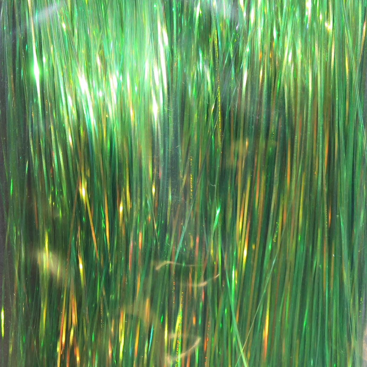 Green dyed Pearl Flashabou tinsel strands, iridescent metallic fly tying material with gold and emerald highlights