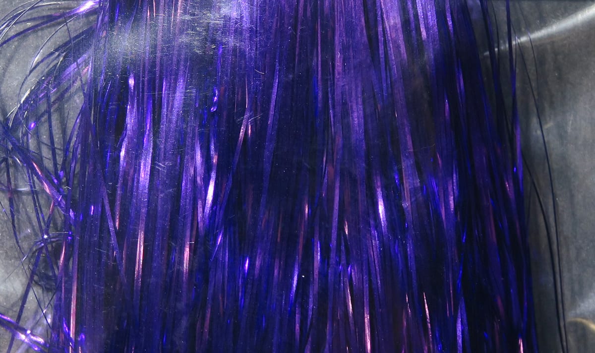 Purple iridescent Hedron Flashabou tinsel strands with reflective metallic sheen, thin ribbon style for fly tying.