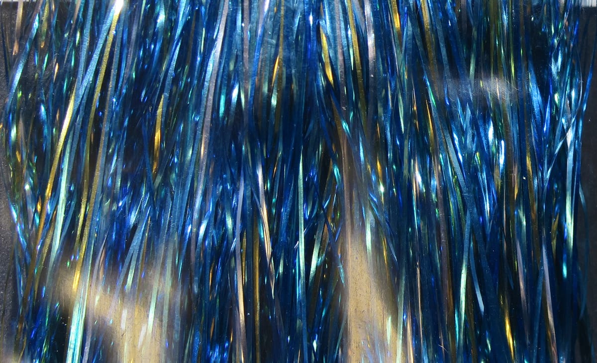 Iridescent metallic blue Flashabou tinsel strands for fly tying with gold and green highlights