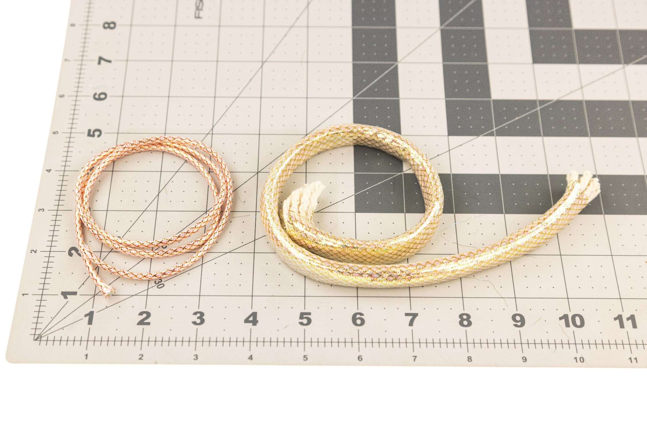 Coiled Hedron Flashabou body tubing in iridescent gold and pink braided material on grid cutting mat