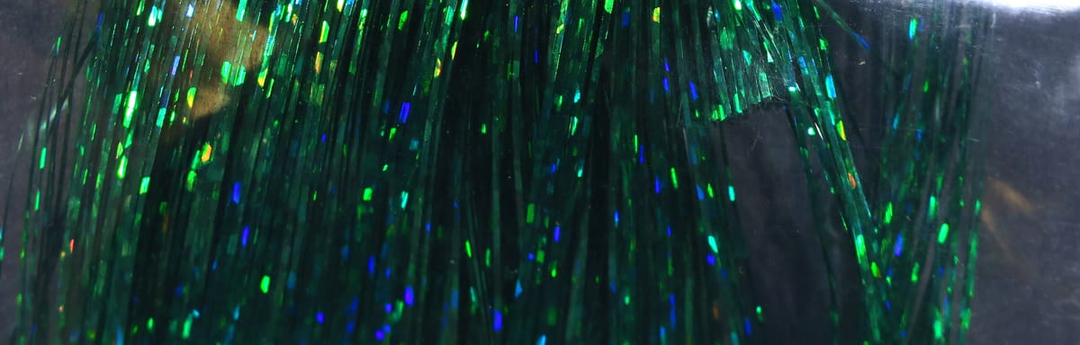 Green holographic Flashabou strands with blue-green iridescent flashes, metallic tinsel fibers for fly tying