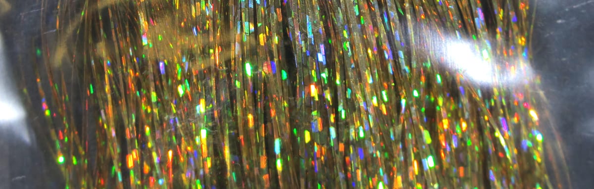 Gold holographic Flashabou tinsel strands with rainbow reflections, thin metallic fly-tying material